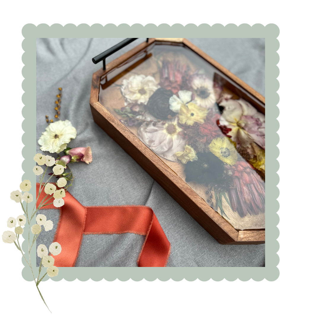 Resin wooden tray with pressed flowers and a red ribbon on a gray surface