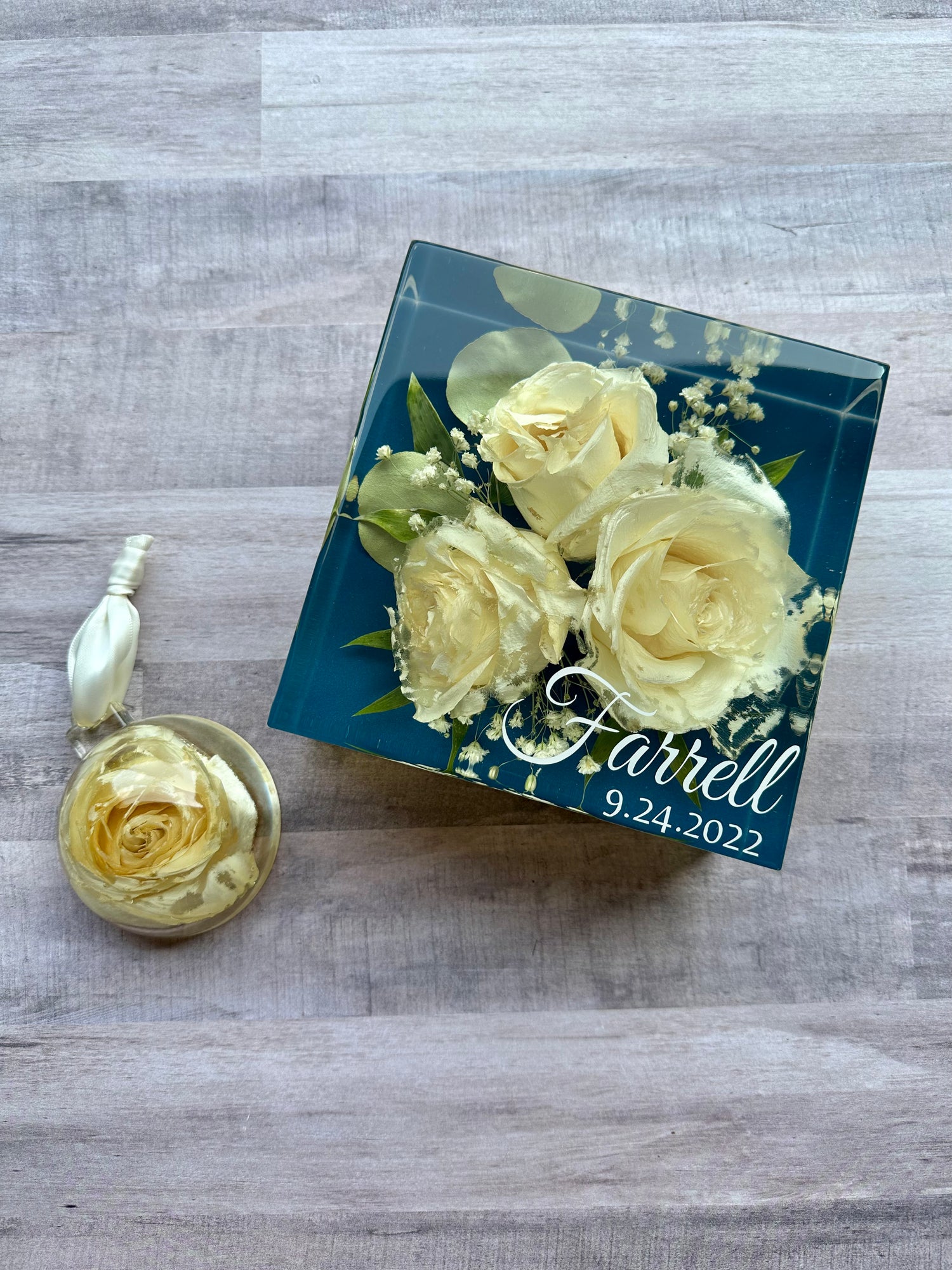 Decorative box with preserved yellow roses and a matching pendant on a wooden surface