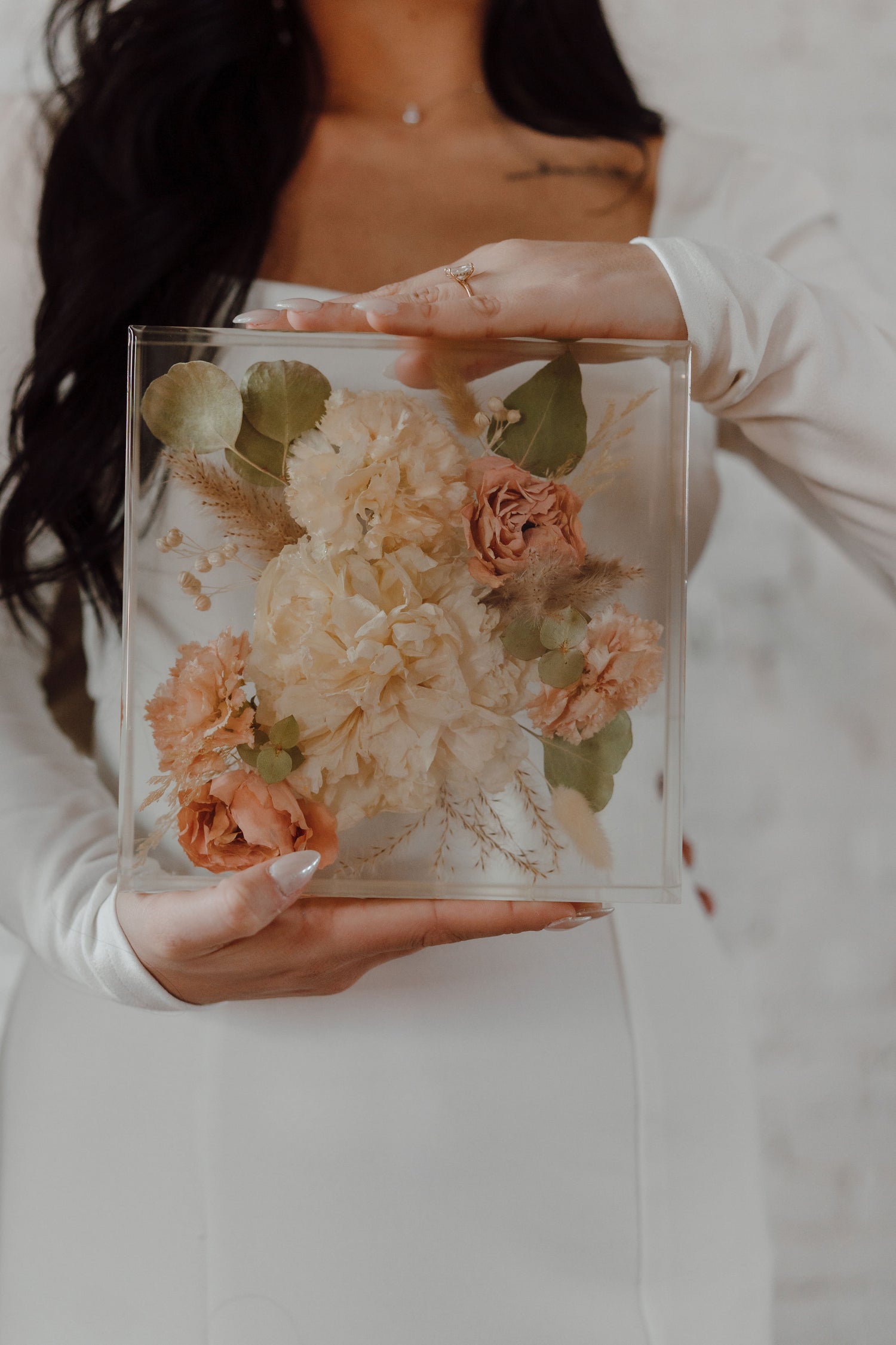Person holding a transparent resin box with preserved flowers.