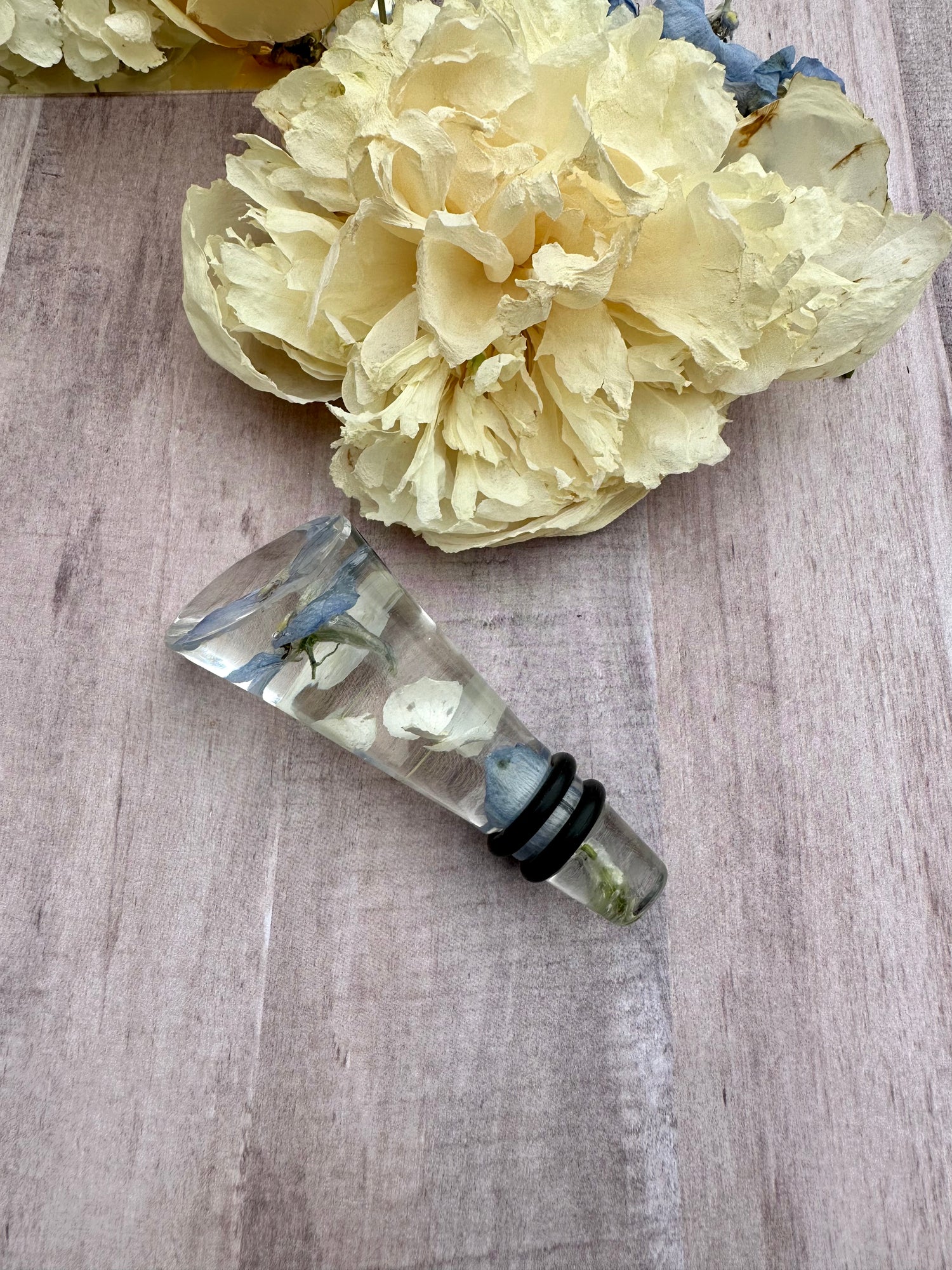 Clear rein wine stopper  with floral preservation on a wooden surface