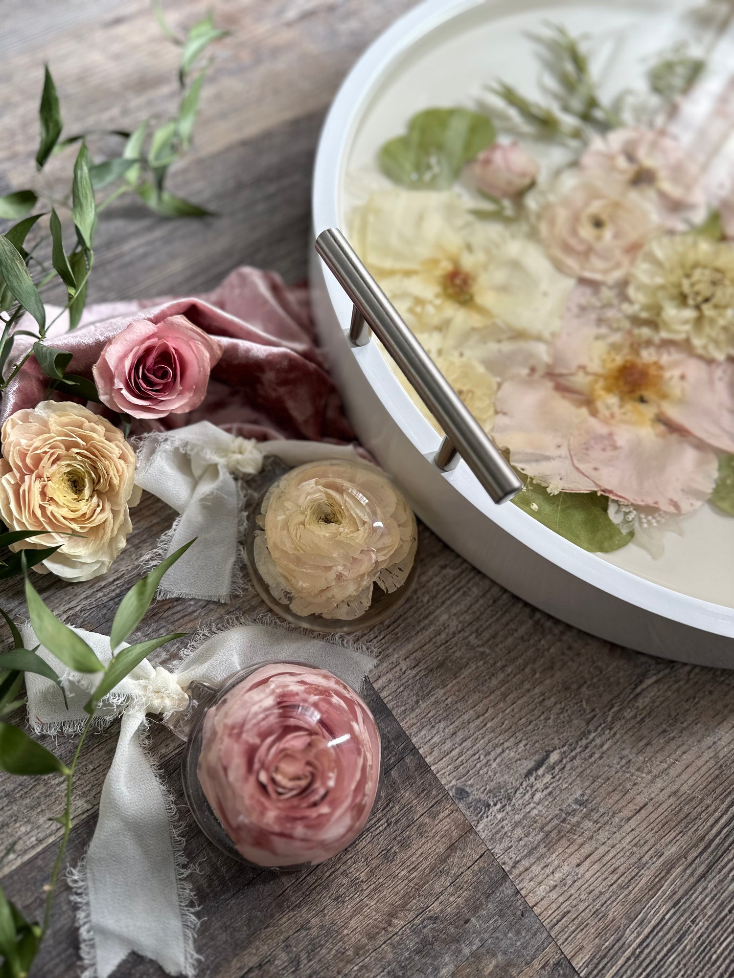 Decorative pink rose and white resin tray with floral preservation on a wooden surface
