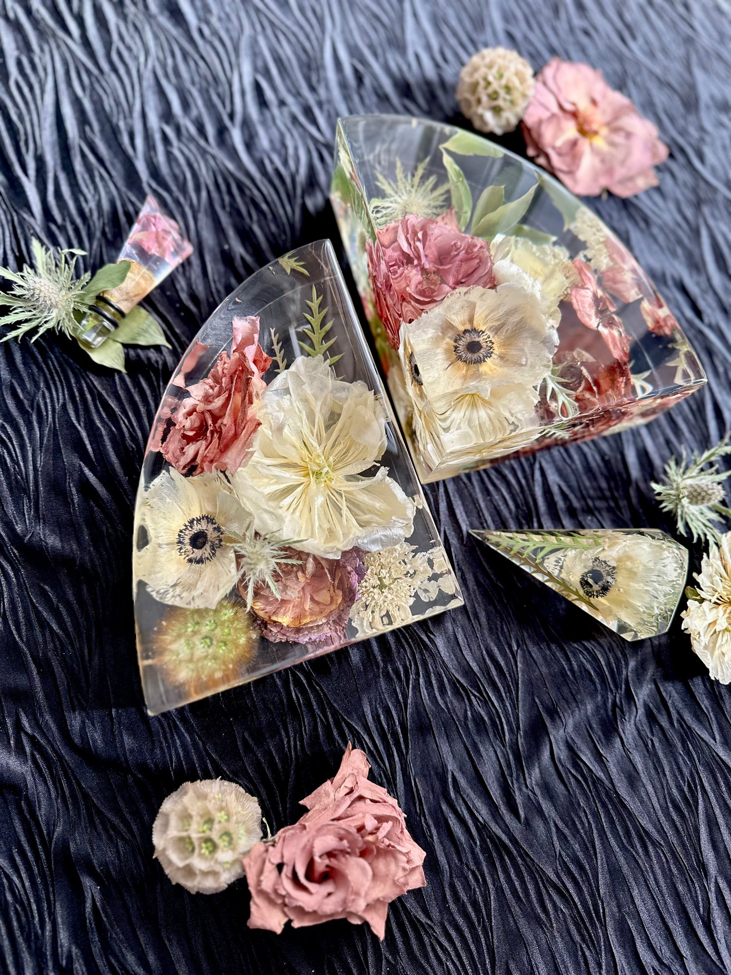 Decorative resin pieces with pressed flowers on a dark textured surface