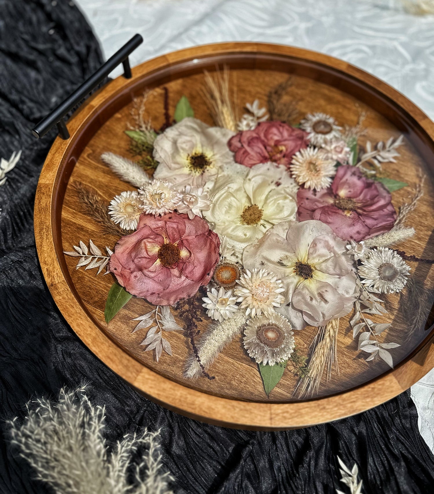 Wooden tray with pressed flowers and leaves on a textured surface