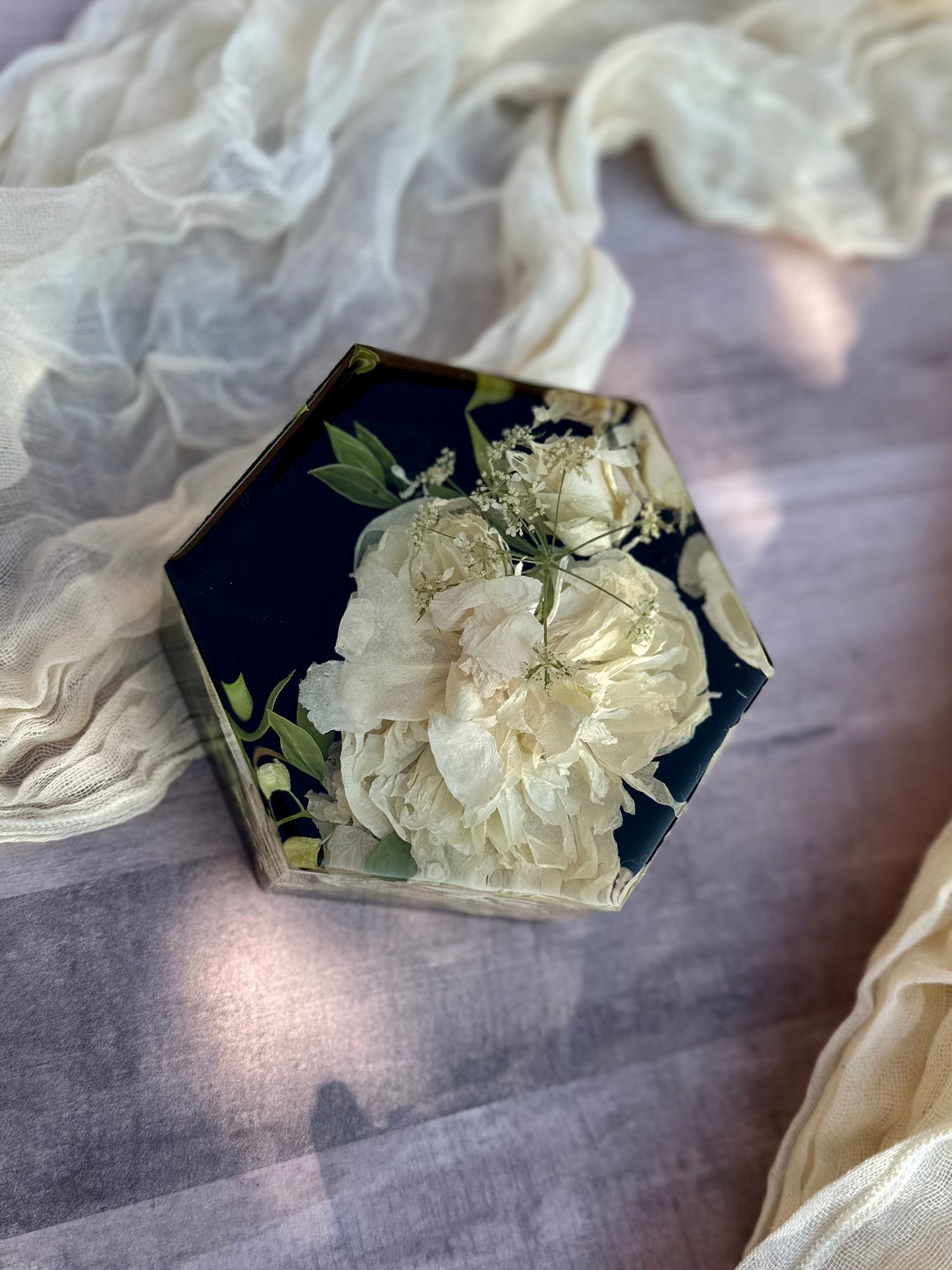 Hexagonal resin with pressed flowers on a textured fabric background