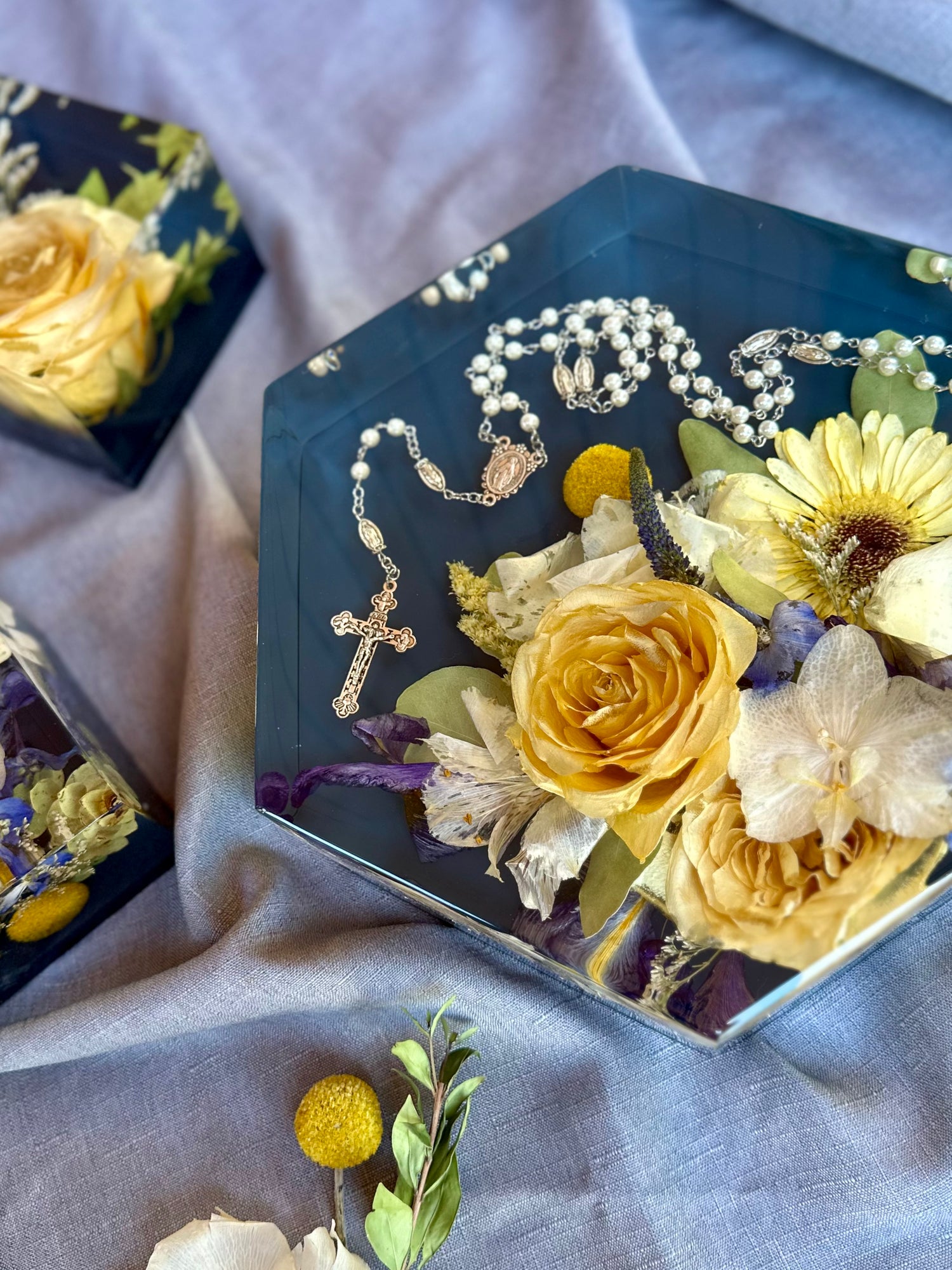 Decorative resin hexagon with flowers and a rosary on a textured surface