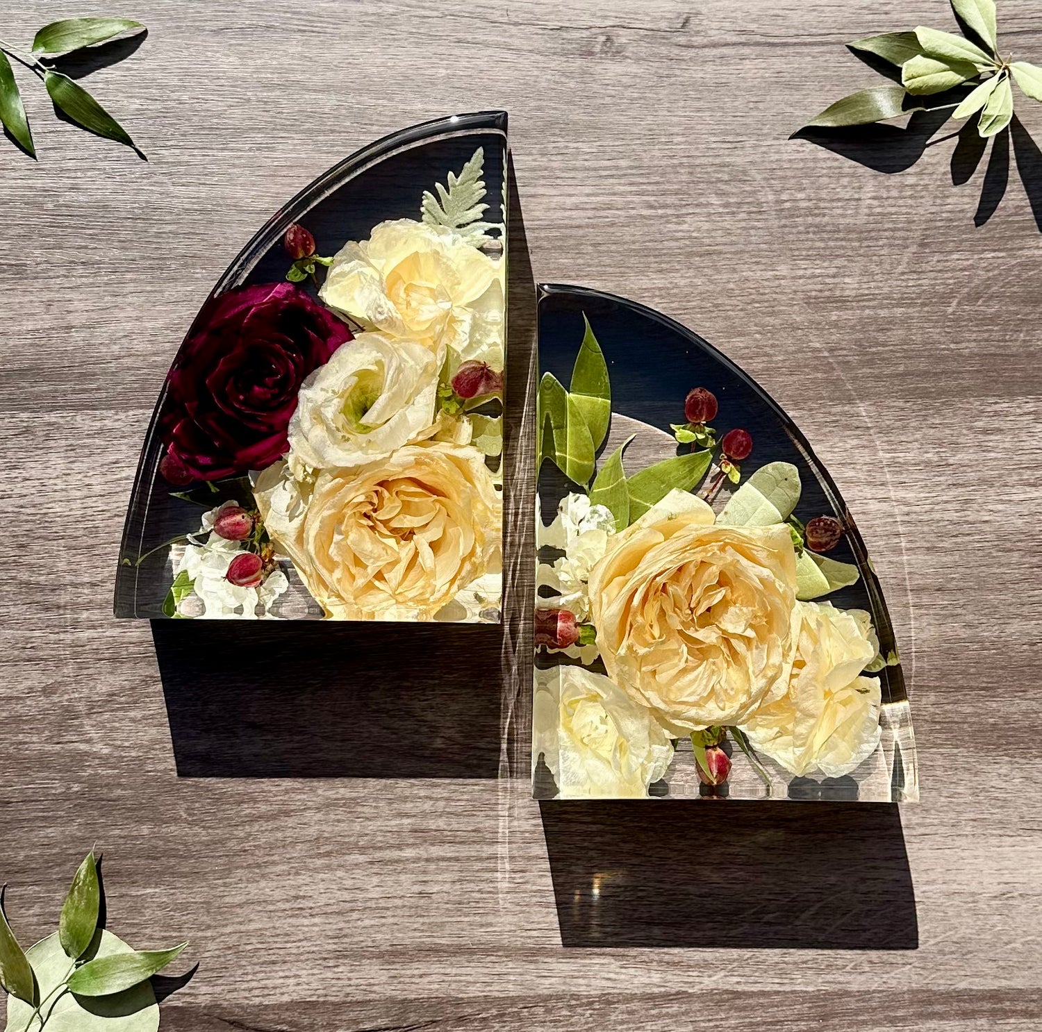 Two resin bookshelf end blocks  with flowers on a wooden surface