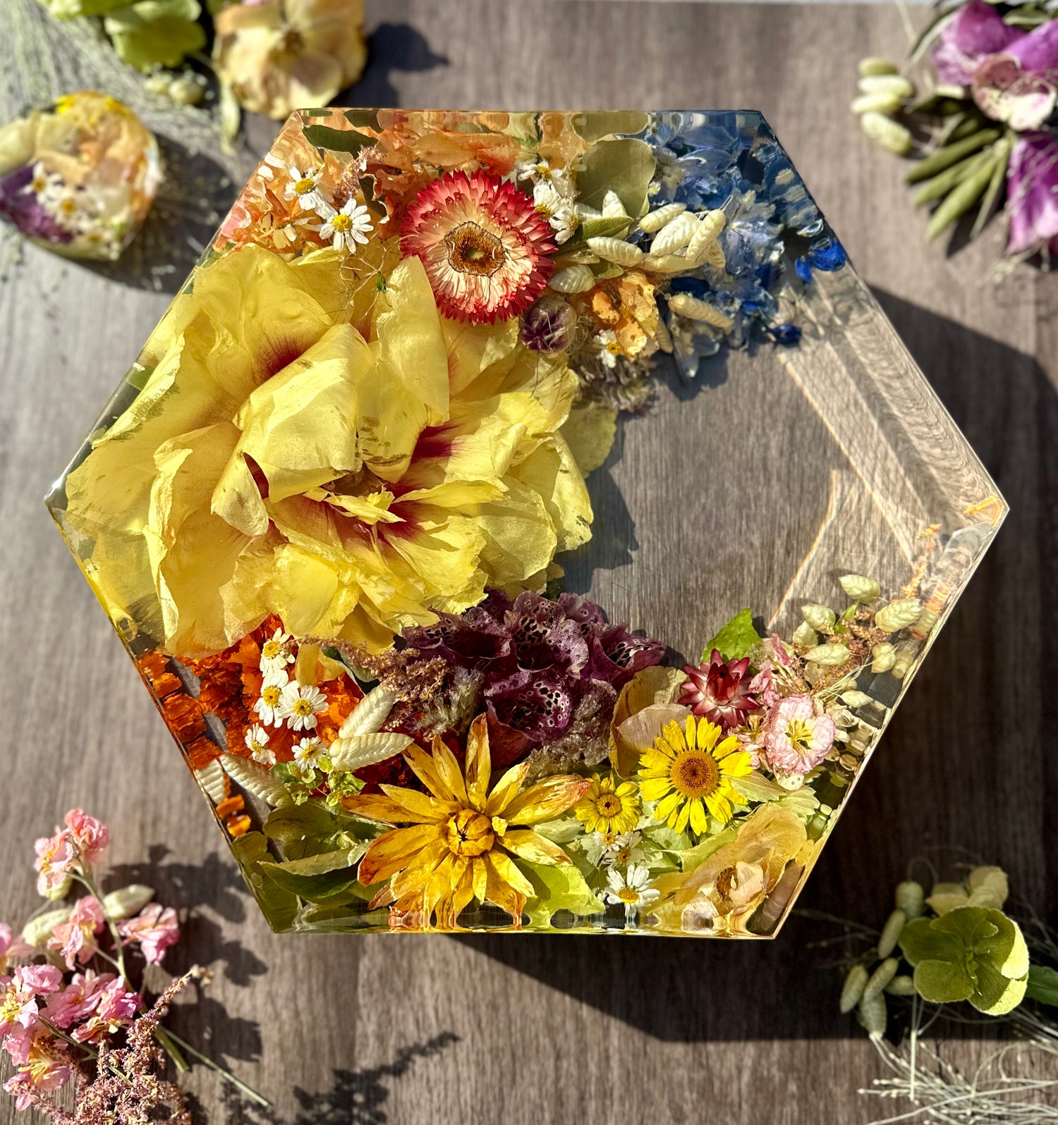 Hexagonal resin block with pressed flowers on a wooden surface