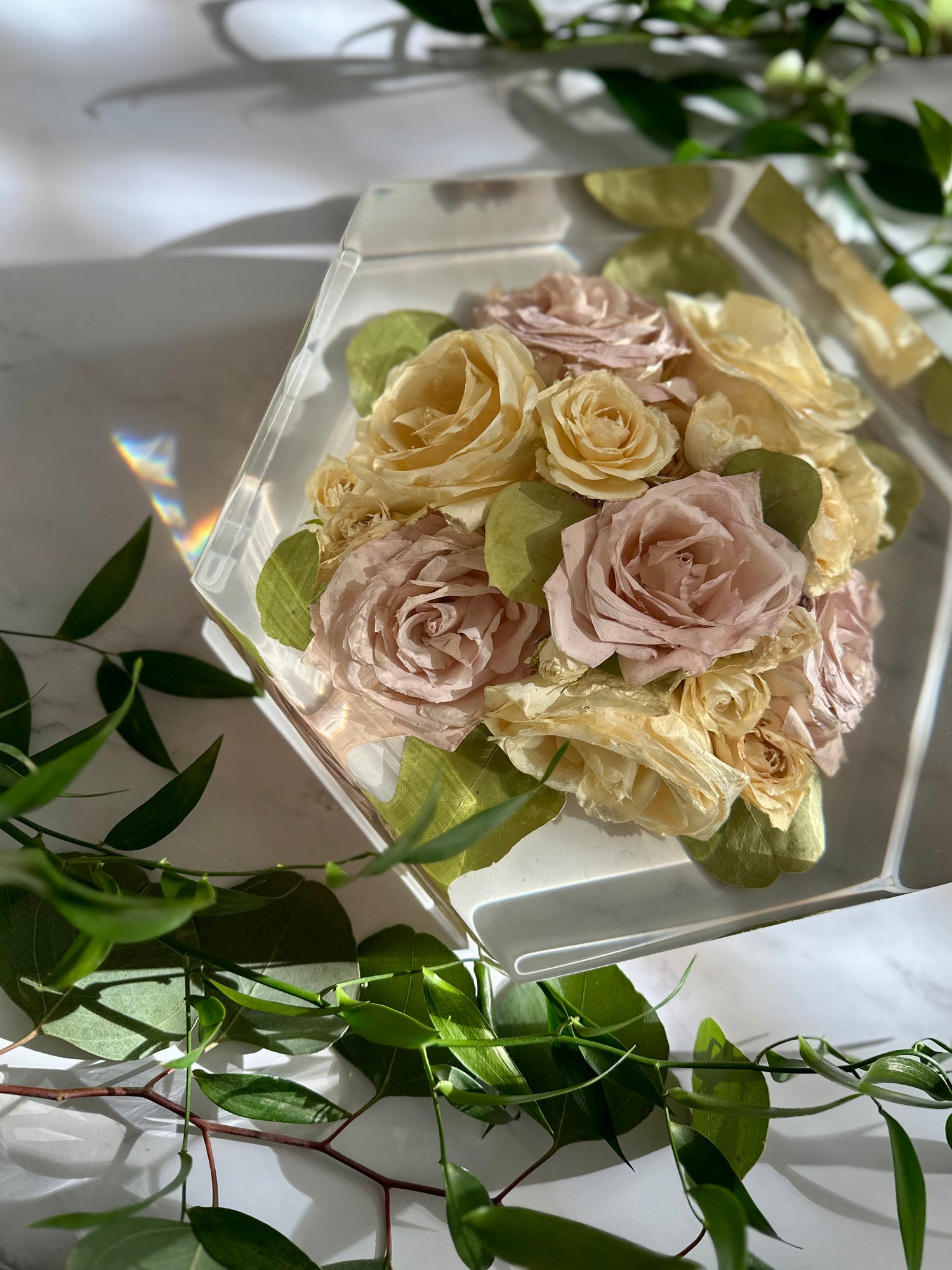 Preserved flower arrangement in a resin hexagon with green leaves around